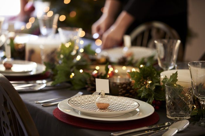 Christmas table setting with bauble name card holder arranged on a plate and green and red table decorations